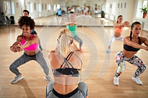 Female instructor with headset show warming exercises to practitioners