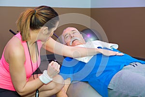 Female instructor helping senior man stretching back