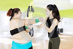 Female instructor helping woman exercising