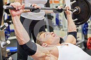 Female instructor helps athlete to put barbell on