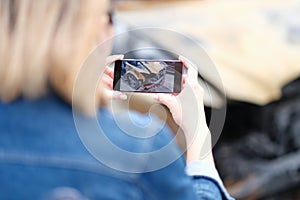 Female insurance agent takes photo of burnt-out car on phone