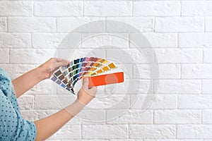 Female interior designer with color palette samples near brick wall, closeup