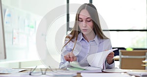 Female intern manager student leafs through journal of entries at workplace in office