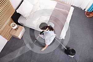 Female Janitor Cleaning Carpet With Vacuum Cleaner