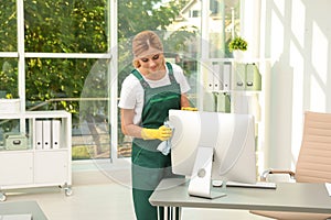 Female janitor cleaning computer monitor with rag