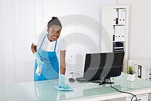 Female Janitor Cleaning Desk With Rag