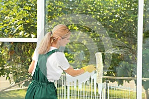Female janitor cleaning window