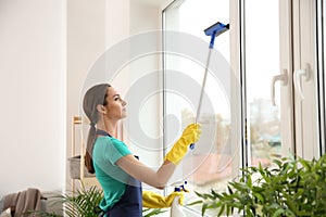Female janitor cleaning window in flat