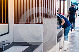 Female janitor using fabric and a detergent cleaning sink and tap