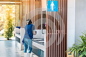 Female janitor using fabric and a detergent cleaning sink and tap