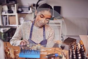 Female Jeweller At Bench Working On Ring With File In Studio