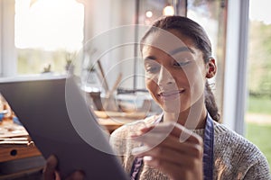 Female Jeweller Comparing Ring With Drawn Design On Digital Tablet In Studio