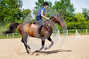 Female jockey galloping on horseback between jumps