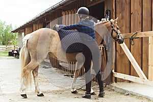 Female Jockey Placing A Saddle Pad On The Back Of Her Horse To Protect From Sores photo