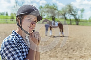 Female Jockey Putting On A Helmet And Getting Ready For Horse Riding Competition