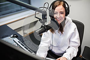 Female jockey smiling while communicating on microphone in radio