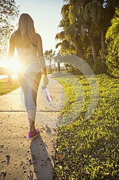 Female jogger in a city park view from behind