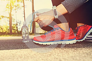 Female jogger tying her running shoes