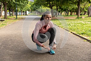 Female jogger tying her shoe laces in the park