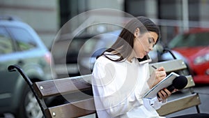 Female journalist making notes and talking phone, preparing for reportage