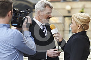 Female Journalist With Microphone Interviewing Businessman