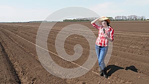 Female journalist tells for TV news report about Modern Agriculturally cultivation. plowed agricultural field background