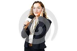 Female journalist using a headphone while speaking on tv news