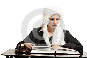 Female judge wearing a wig and black mantle with judge gavel an