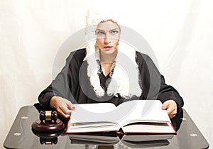 Female judge wearing a wig and black mantle with judge gavel an