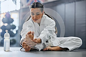 . Female karate school student doing a warmup, stretch or exercise with serious, determine and focus before workout