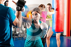 Female kick boxer with trainer in sparring