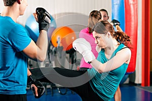 Female kick boxer with trainer in sparring