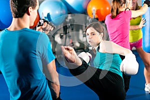 Female kick boxer with trainer in sparring