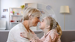 Female kid and granny nuzzling, family generations and connection, closeness photo