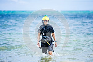 Female kiteboarder student walking in shallow water