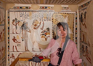 Female Korean tourist and fresco in the south wing end wall of the transverse chamber of TT69 featuring worship of Osiris.