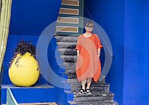 Female Korean tourist standing on steps next to a Purple Queen plant in the Jardin Majorelle in Marrakesh, Morocco.