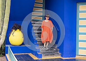 Female Korean tourist standing on steps next to a Purple Queen plant in the Jardin Majorelle in Marrakesh, Morocco.