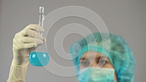 Female laboratory worker holding tube with blue liquid in hand, biology science