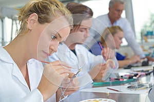 Female laboratory worker painting false tooth