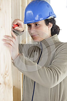female labourer using screwdriver on wood panel