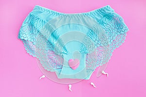 Female lace blue panties with a pink heart and spermatozoa on a pink background.