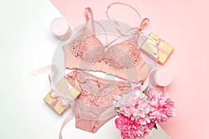 Female lace pink underwear with a pink ribbon and candles on a pink background