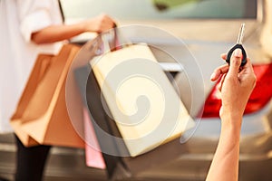 Female Ladies carrying Colorful Shopping Bags in the parking lots Concept. Lady hand using remote control to send signal to unlock