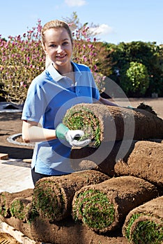 Female Landscape Gardener Laying Turf For New Lawn