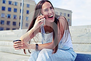 female laughing during her phone talk while having a coffe