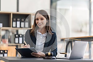 Female lawyer happily working on laptop computer with hammer and legal book scales