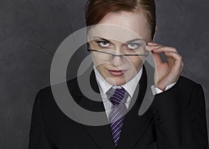 Female lawyer holding a big book with serious expression, woman in a man`s suit, tie and glasses