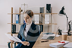 female lawyer in suit with documents in hands at workplace