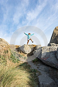 Female leaps off of a large rock along the Oregon Coast